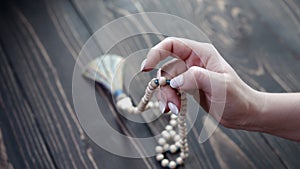 Woman lit hand counts malas strands of wooden beads used for keeping count during mantra meditations. Lady sits on