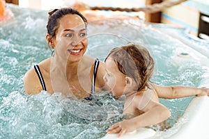 Woman with little child swim together in whirlpool bath