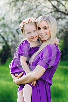 Woman with a little daughter walking through the blooming Apple