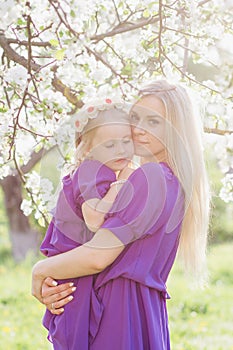 Woman with a little daughter walking through the blooming Apple