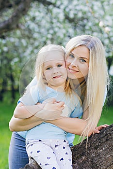 Woman with a little daughter walking through the blooming Apple