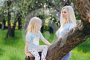 Woman with a little daughter walking through the blooming Apple