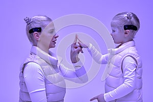 Woman with little girl in futuristic costume wearing smart led glasses of virtual reality while touching air. Augmented
