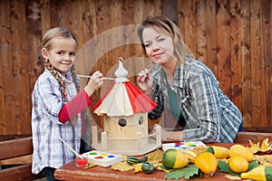 Woman and little girl painting a bird house