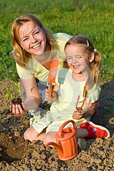 Woman and little girl planting tomato seedlings