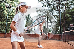 Woman and little girl playing tennis and waiting for the service