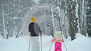 Woman and little girl skiing in the forest