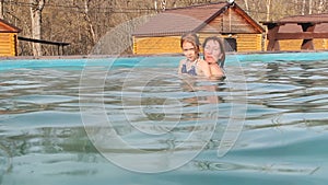 Woman and the little girl swims in the outdoor pool