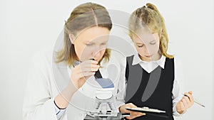 Woman and little girl using microscope.
