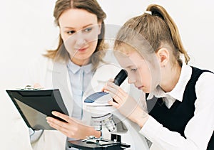 Woman and little girl using microscope.