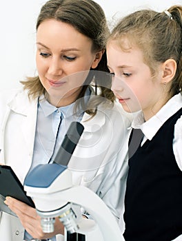 Woman and little girl using microscope.