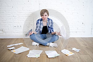 Woman at living room floor with calculator and bank and bills paperwork and documents doing domestic financial accounting