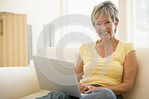 Woman in living room with laptop smiling