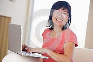 Woman in living room with laptop smiling