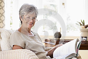 Woman in living room reading book smiling