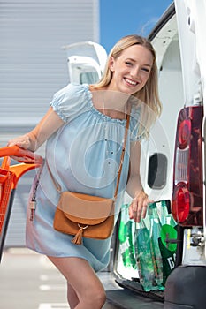 woman loading car with grocery bags