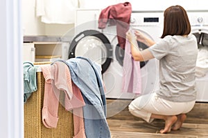 Woman Loading Dirty Clothes In Washing Machine For Washing In modern Utility Room