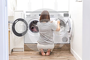 Woman Loading Dirty Clothes In Washing Machine For Washing In modern Utility Room