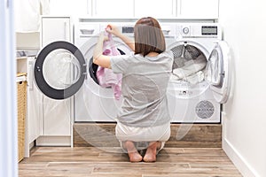 Woman Loading Dirty Clothes In Washing Machine For Washing In modern Utility Room