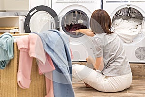 Woman Loading Dirty Clothes In Washing Machine For Washing In modern Utility Room