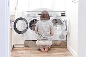 Woman Loading Dirty Clothes In Washing Machine For Washing In modern Utility Room