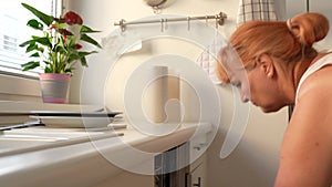 Woman loading dirty dishes into dishwasher in home kitchen