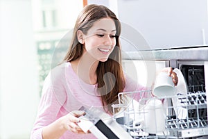 Woman loading dishwasher photo