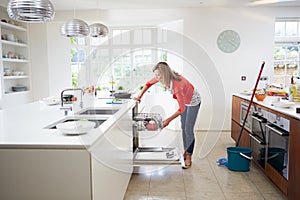 Woman Loading Plates Into Dishwasher