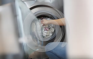 Woman loading washing machine with dirty clothes, taking out clean stuff