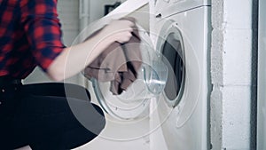 A woman loads a washing machine, wearing robotic prosthesis, close up.