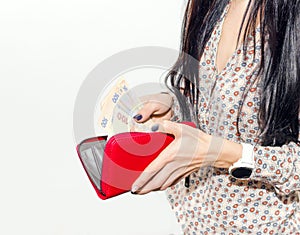 Woman with long black hair puts paper money in a red purse