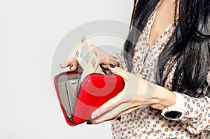 Woman with long black hair puts paper money in a red purse