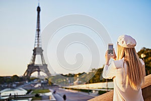 Woman with long blond hair taking photo of the Eiffel tower