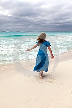 Woman in a long blue dress on the  stormy sea coast