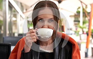 Woman with long brown hair, drinking coffee or tea, using her laptop on a restaurant`s terrace. Concepts of online shopping,