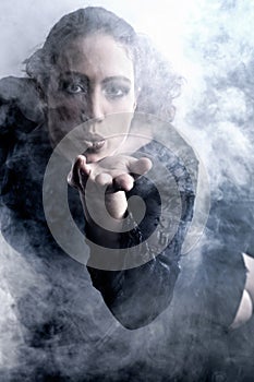 Woman with long curly hair blowing smoke