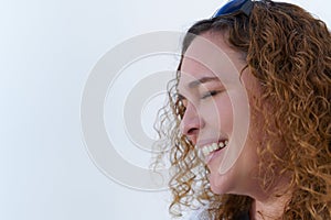woman with long curly hair seen in profile smiling with closed eyes