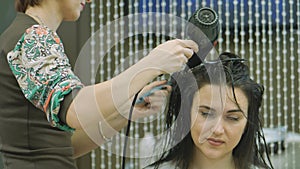 A woman with long dark hair in a beauty salon, hair styling with a master