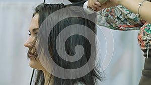 A woman with long dark hair in a beauty salon, hair styling with a master