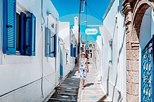 Woman in long dress walking through an alley in greek village Koskinou in Rhodes island in Greece