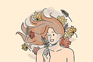 Woman with long flowing hair lies among autumn leaves and smiles rejoicing at onset of september