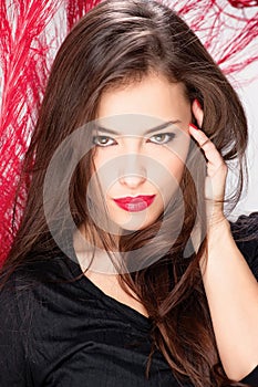 Woman with long hair in front of red feather