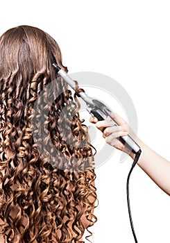 Woman with long hair, hand barber curling irons on white.