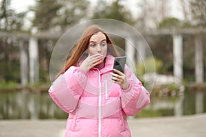 Woman with long hair looks in amazement at something she is seeing on her smartphone