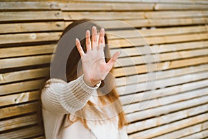 Woman with long hair reaches forward, shielding her face from camera. Concept of privacy, personal space, prohibition of