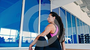 Woman with long hair stretches her back in gym