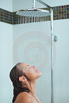 Woman with long hair taking shower under water jet