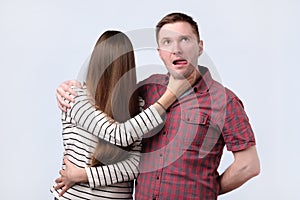 Angry woman try to strangle husband, studio shot photo