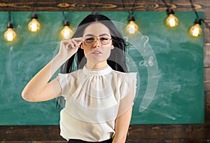 Woman with long hair in white blouse stands in classroom. Strict teacher concept. Lady strict teacher on calm face