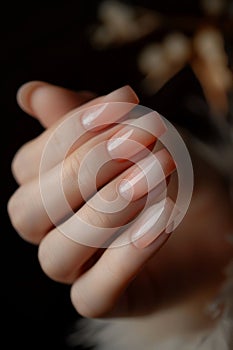 A woman with long nails holding a pink nail polish